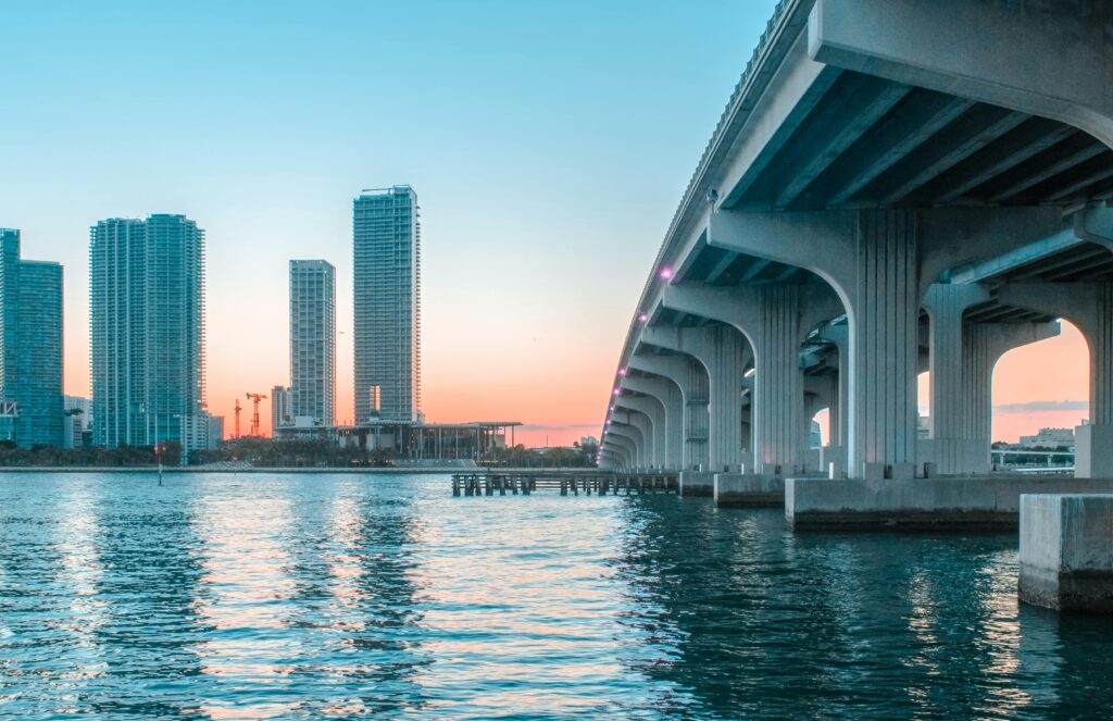 Stunning view of Miami Beach's skyline with a bridge at sunset, reflecting on the water.